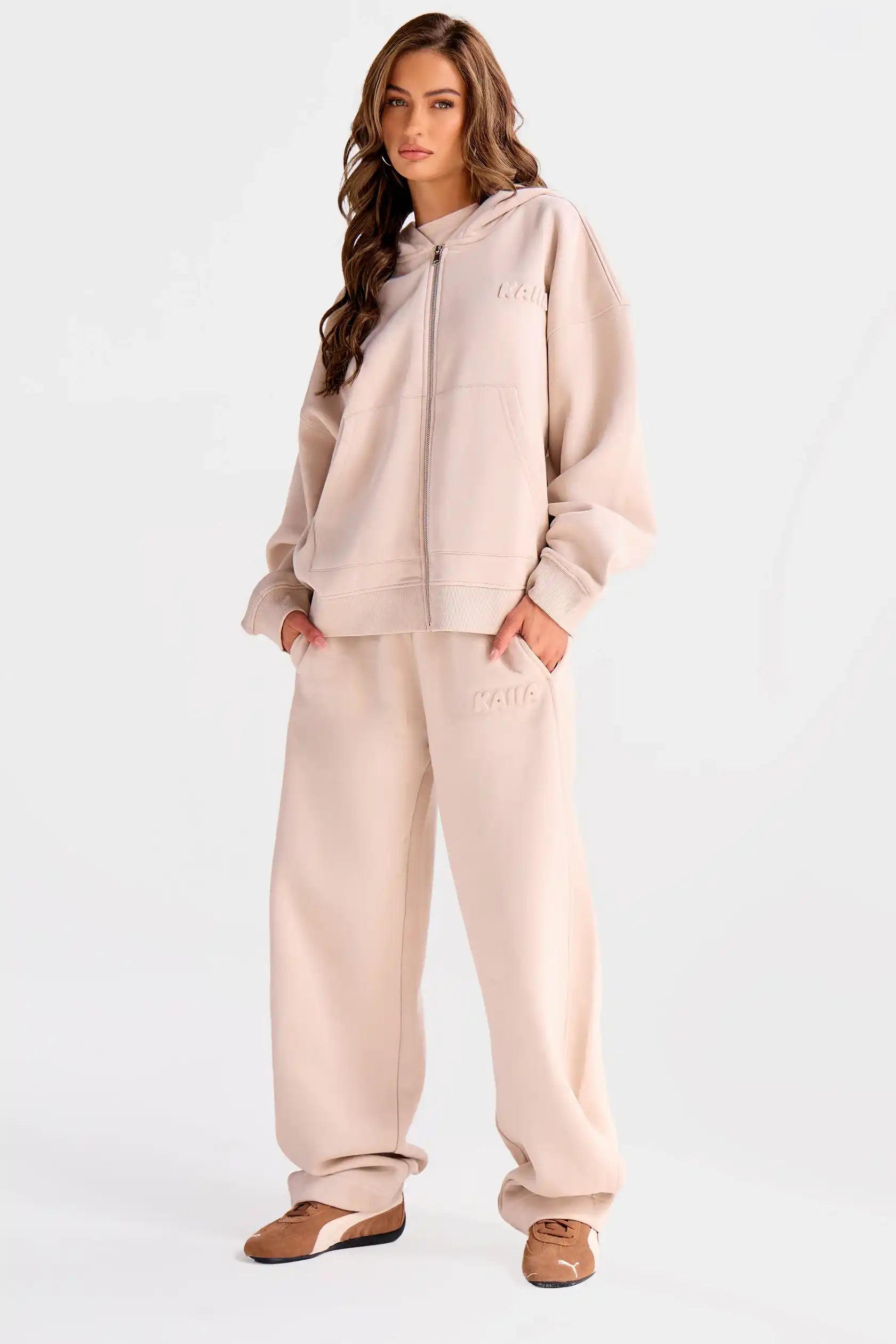 Woman wearing a beige tracksuit on a white background
