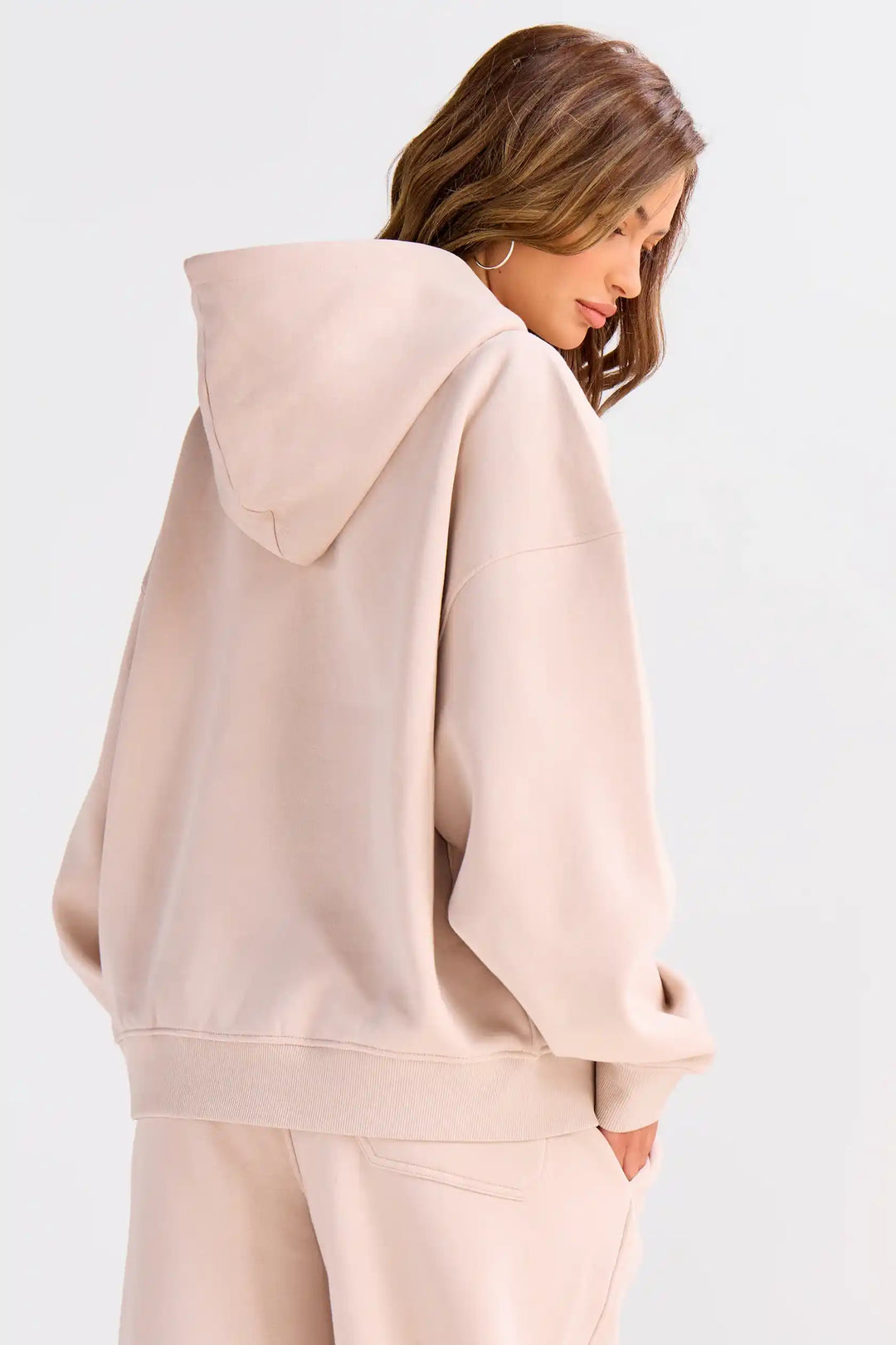 Woman wearing a beige hoodie and pants on a white background